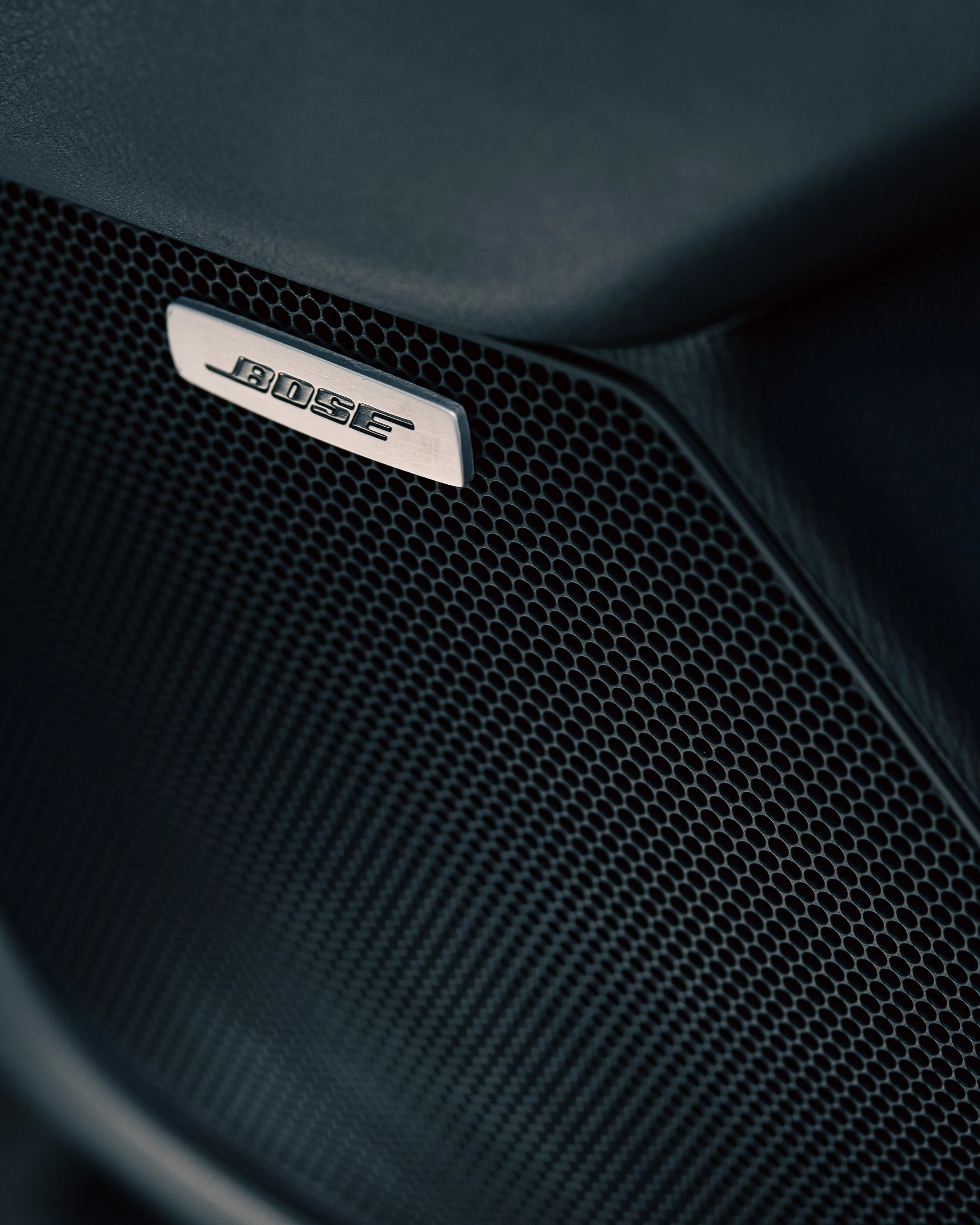 Close-up of a Bose speaker grille with a metallic Bose logo on a black surface.