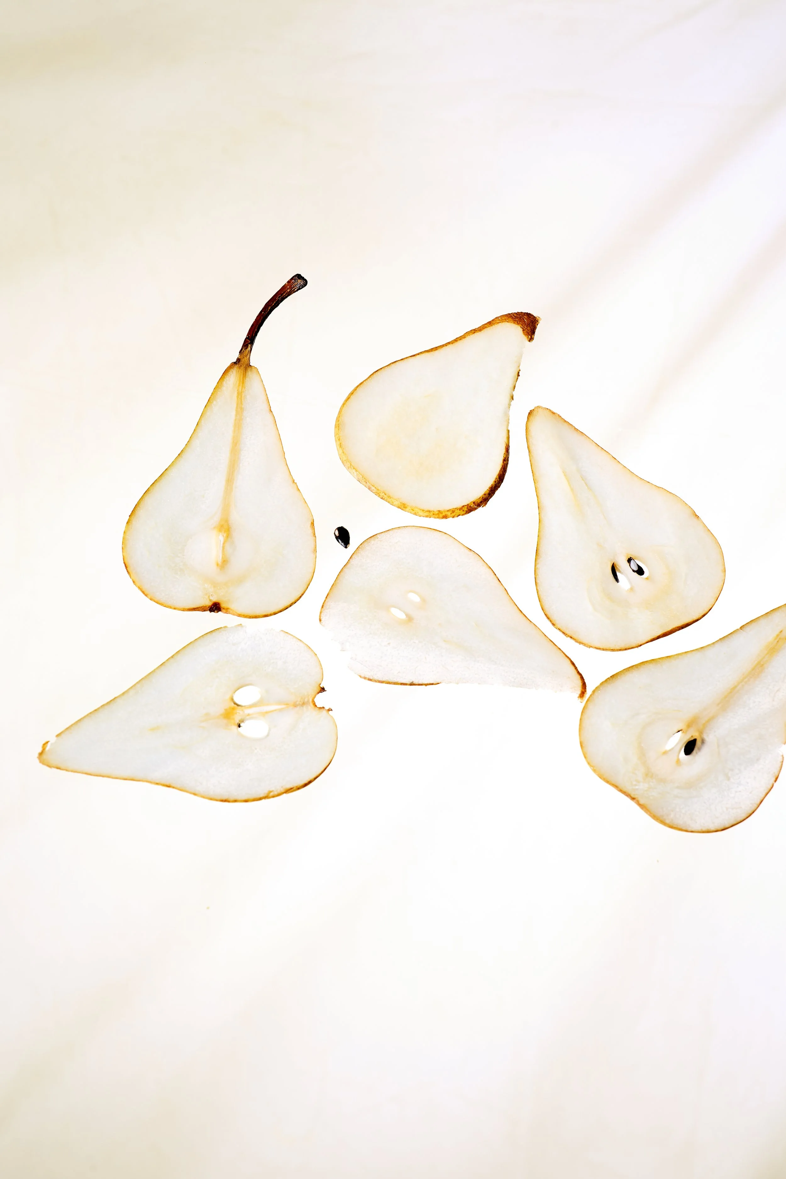 Thin pear slices with brown skin on a white background.