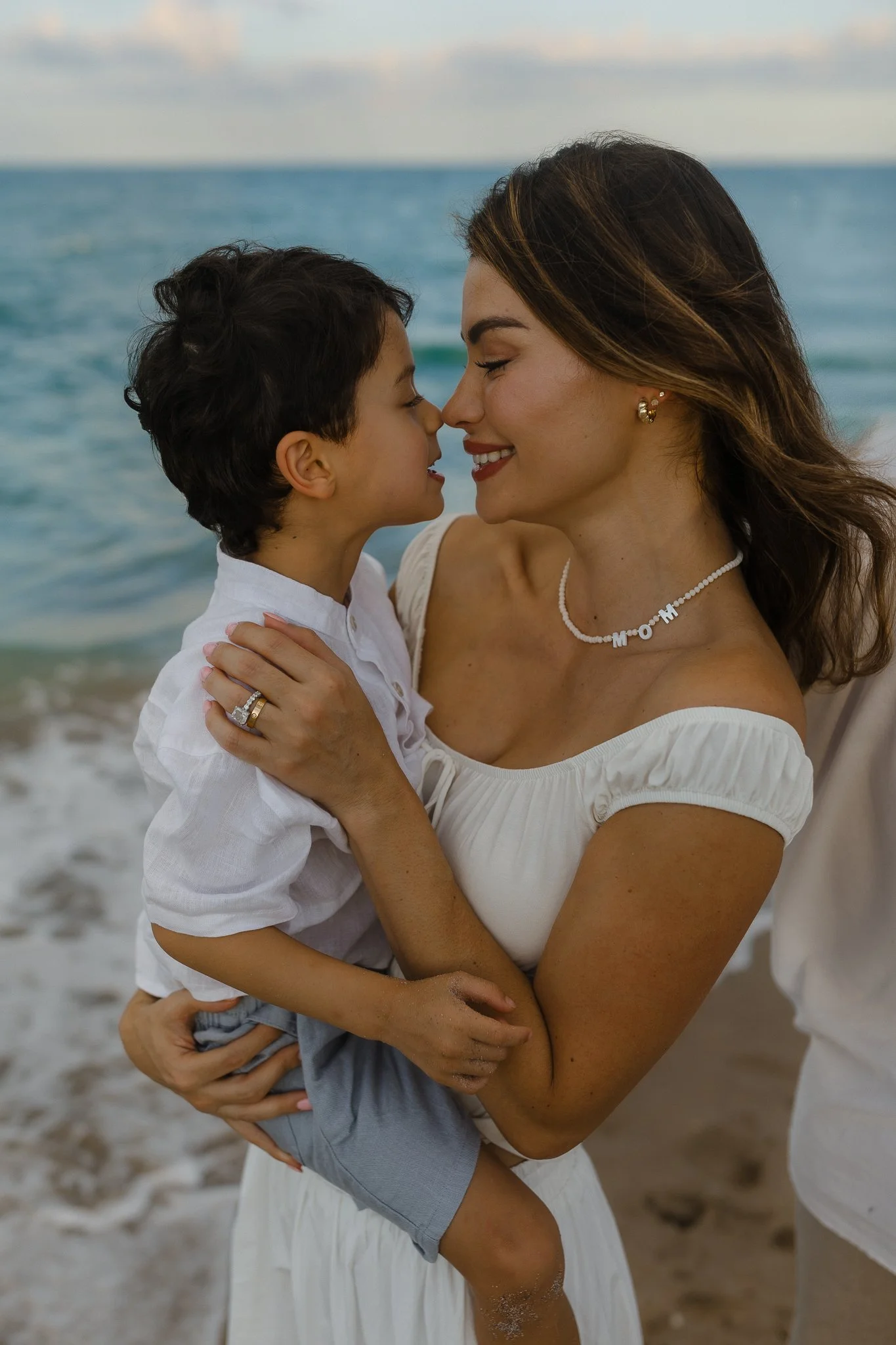 woman holding her son, smiling at each other on the beach