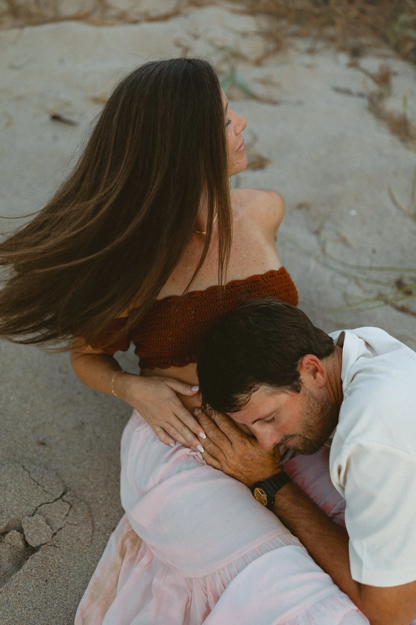 a husband bending down to put his ear on his pregnant wife's belly