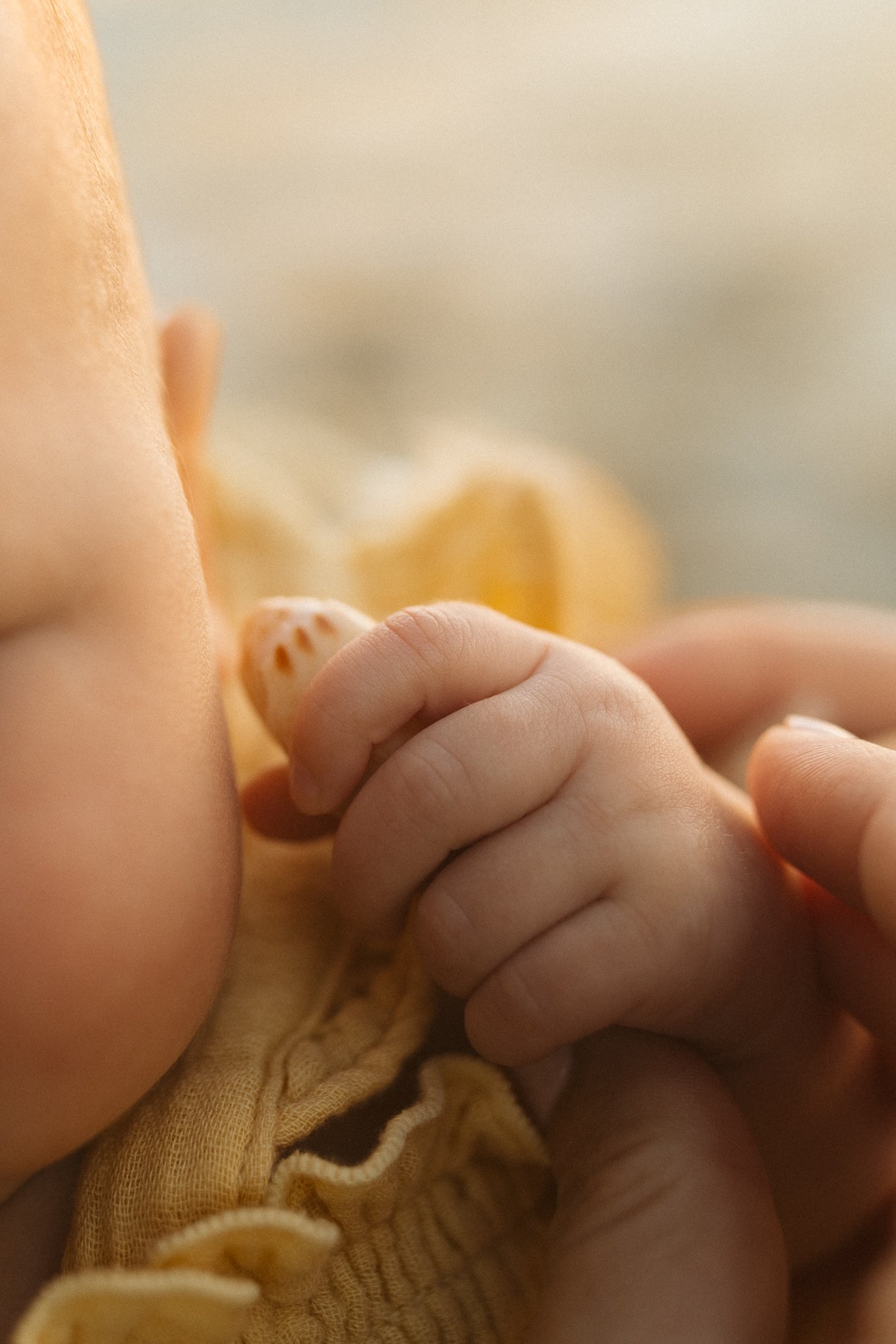 a newborn baby holding a shell close to it's ear