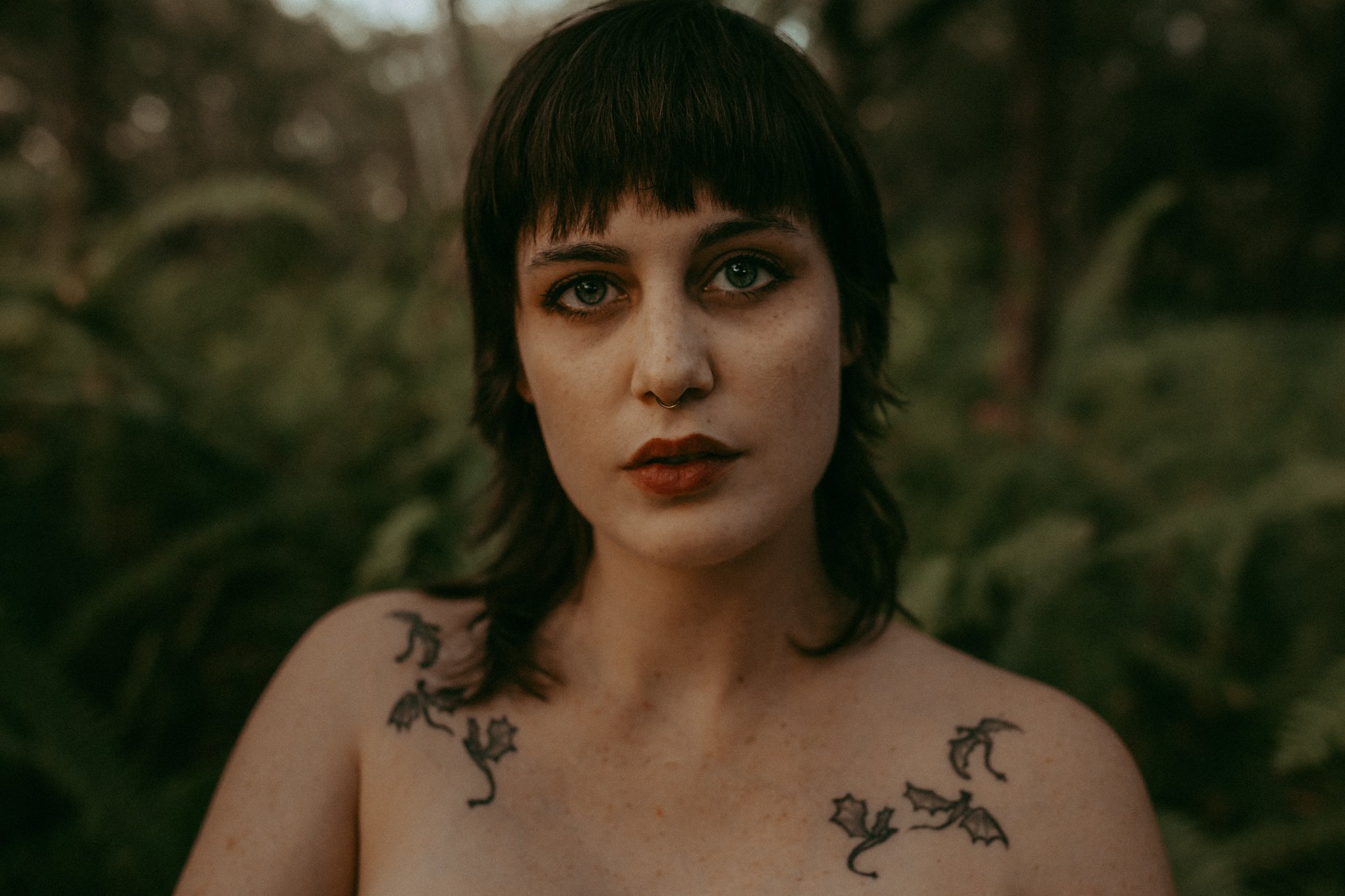 portrait of woman with tattoos in a fern forest