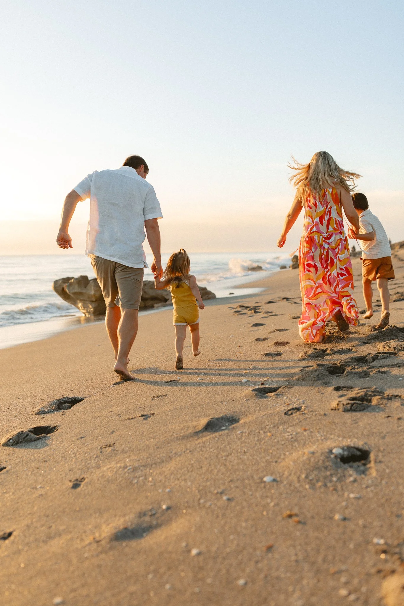a family running down the beach during sunrise
