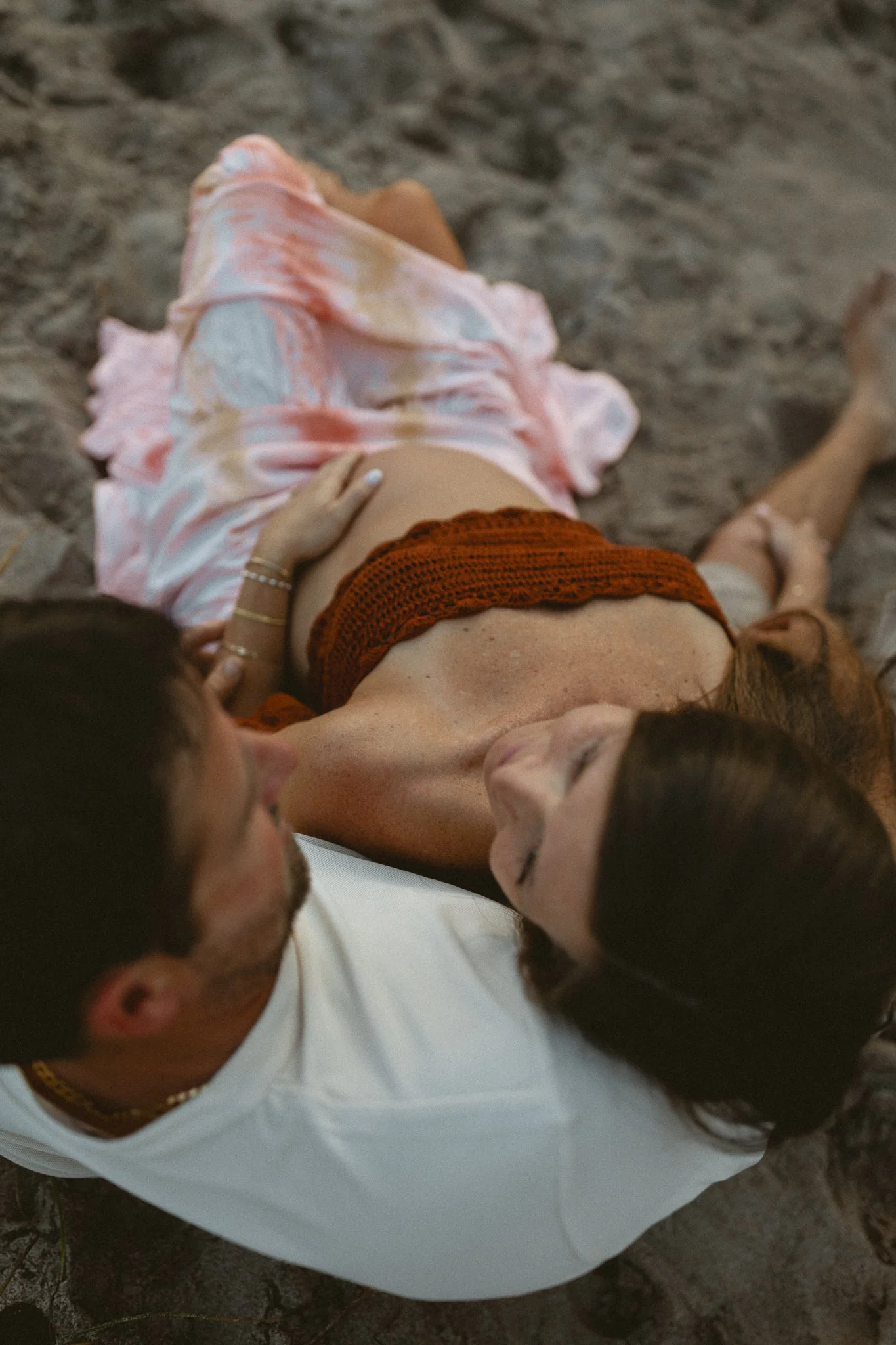 aerial view of a pregnant woman leaning against her husband while sitting and looking at him