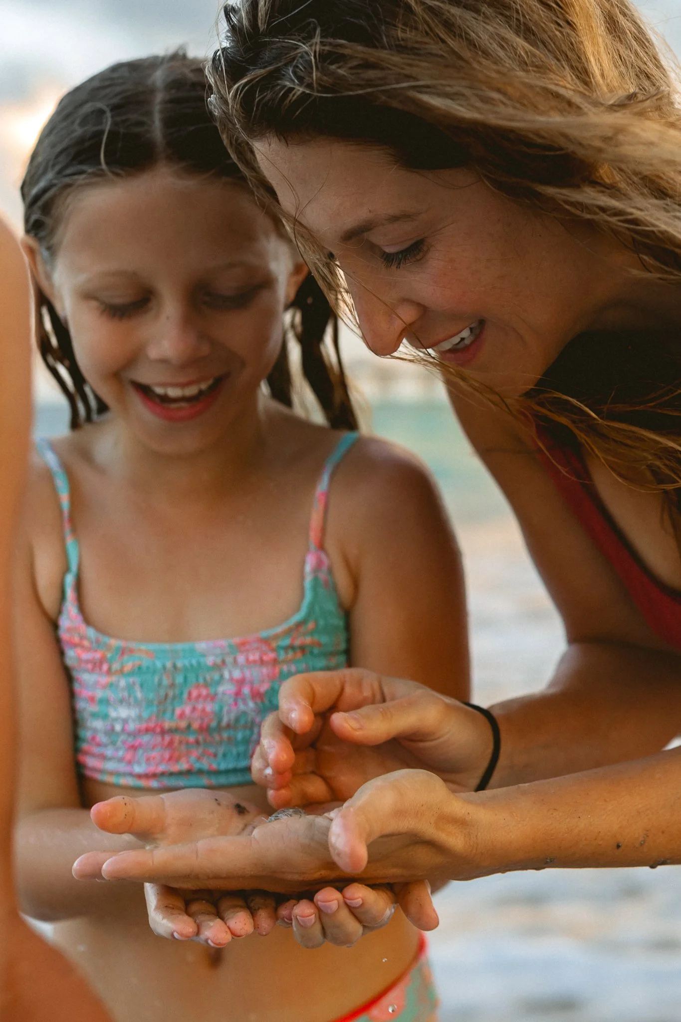 mother and daughter holding a crab on the beach