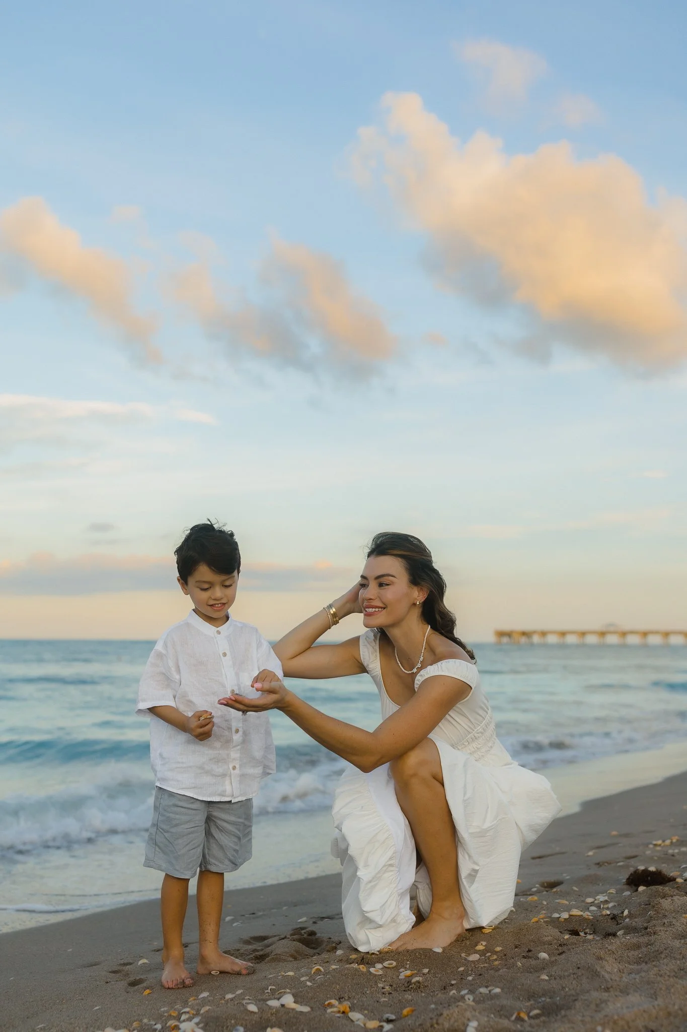 Woman finding shells with her son on a beach during golden hour sunset