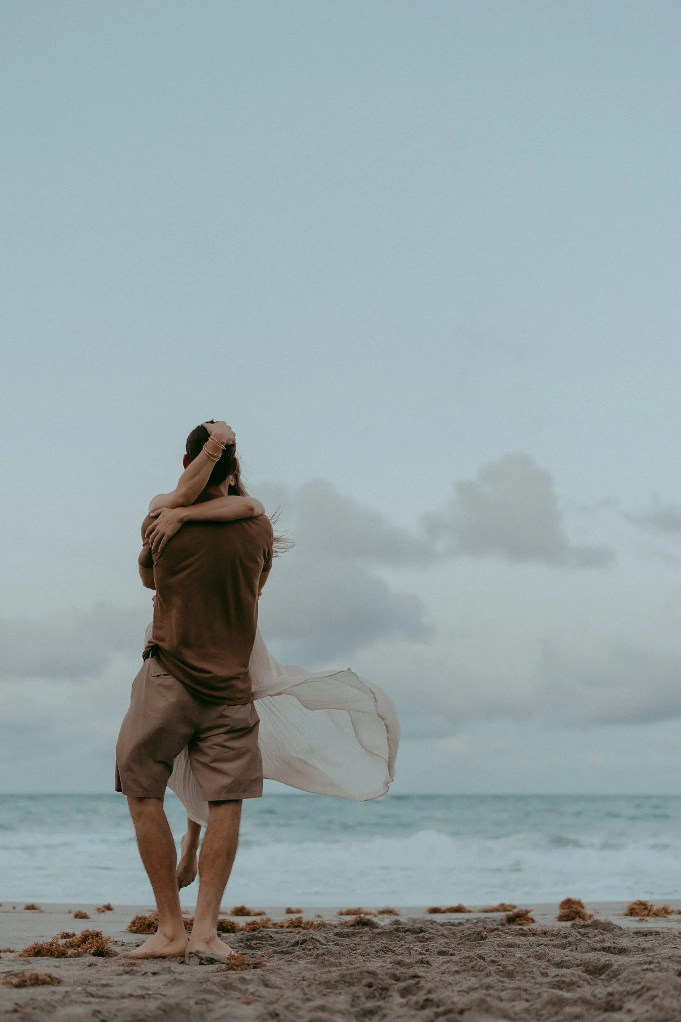 Couple embracing on the beach during sunset with waves in the background