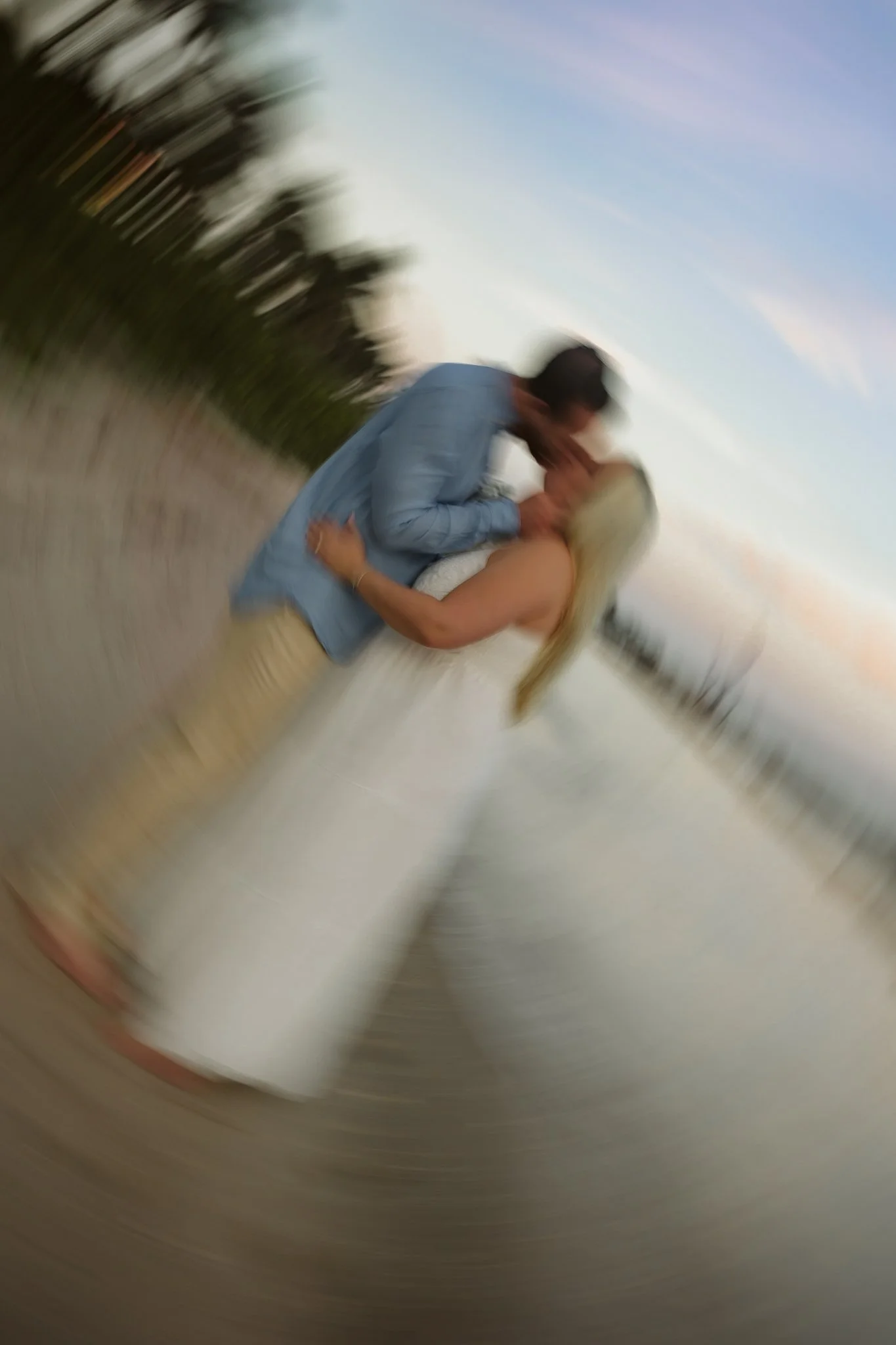 A couple sharing a kiss outdoors during sunset.