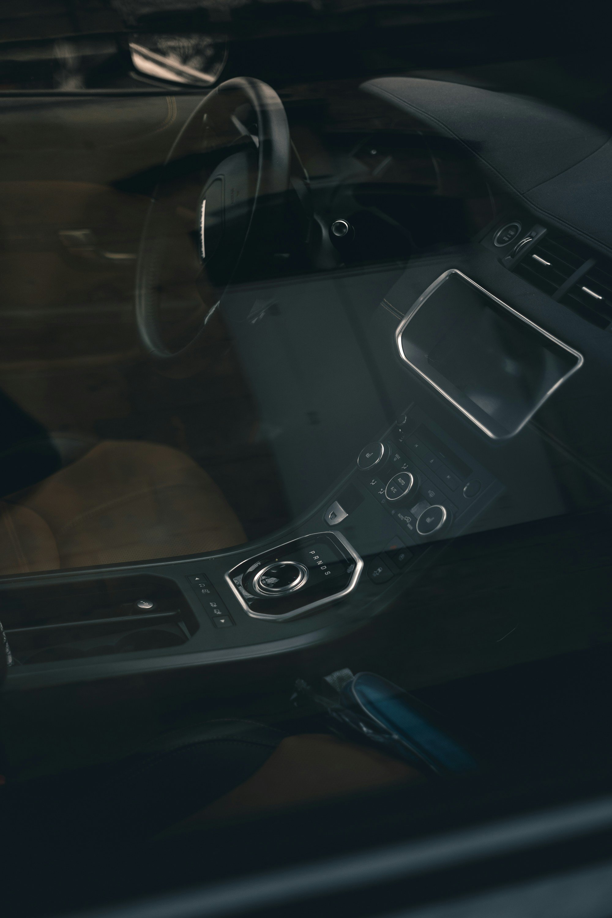 Interior of a modern car showing the steering wheel, center console with gear selector, and dashboard.