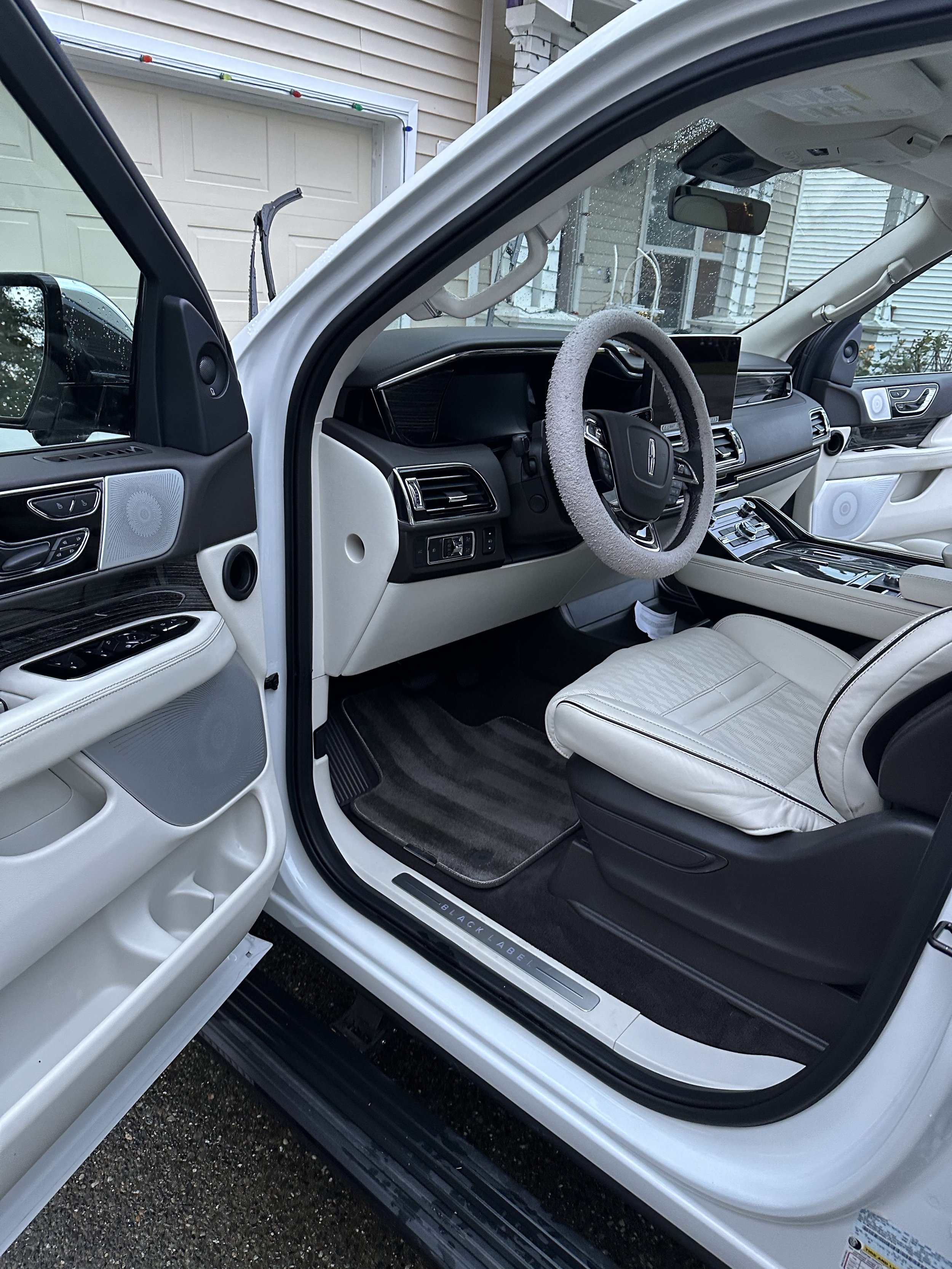 Interior view of a white vehicle with a black steering wheel, cream-colored seats, and a touchscreen display, after the detail.