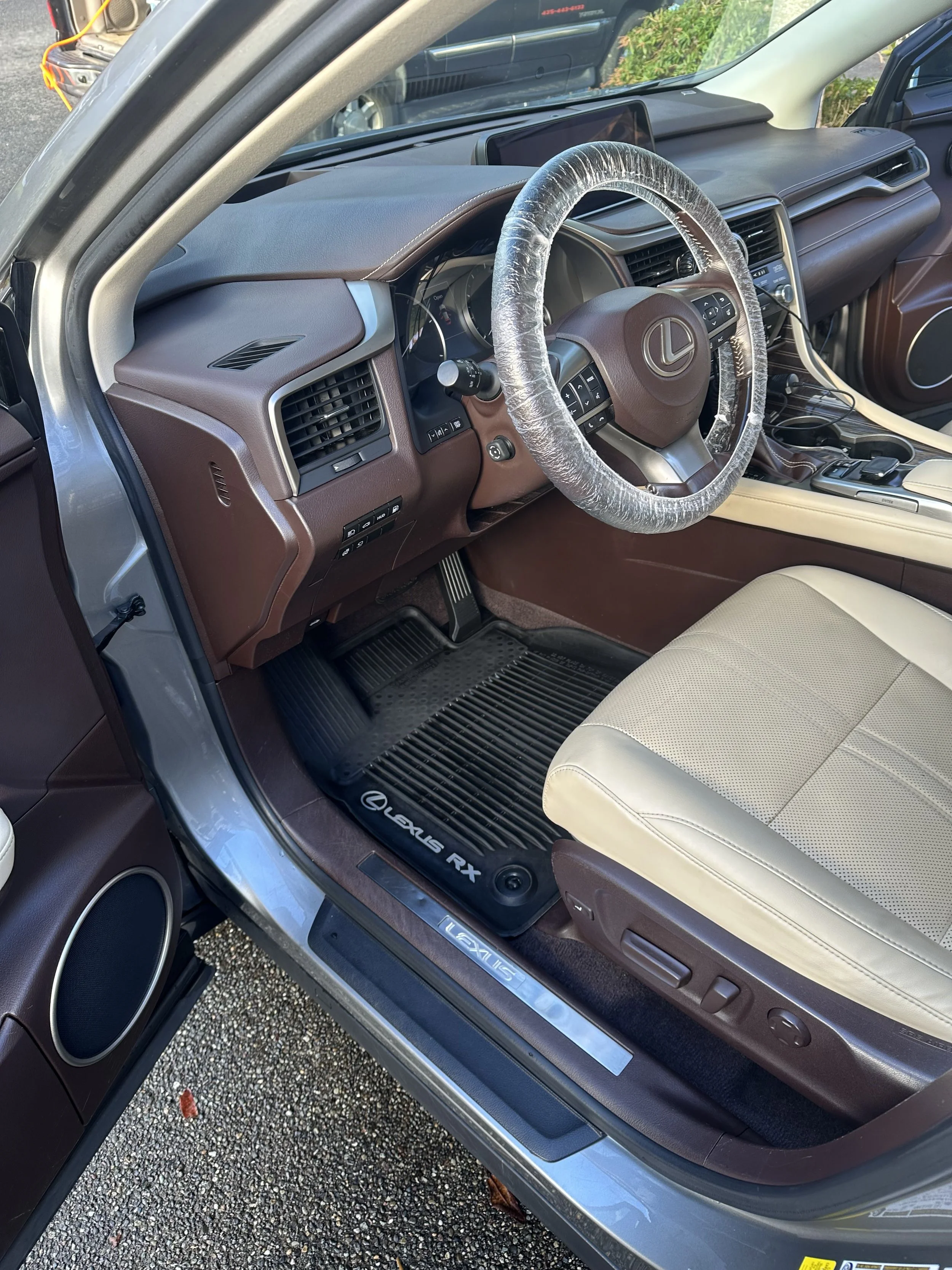 Interior of a Lexus RX vehicle with beige seats, brown dashboard, and a black rubber floor mat.