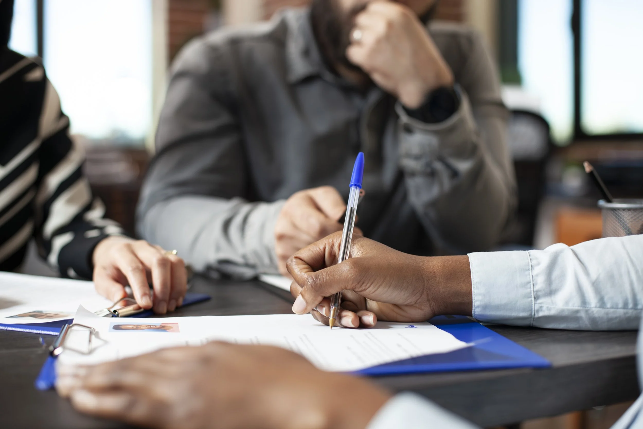 People engaged in a meeting, reviewing photos, and taking notes with a pen and paper.