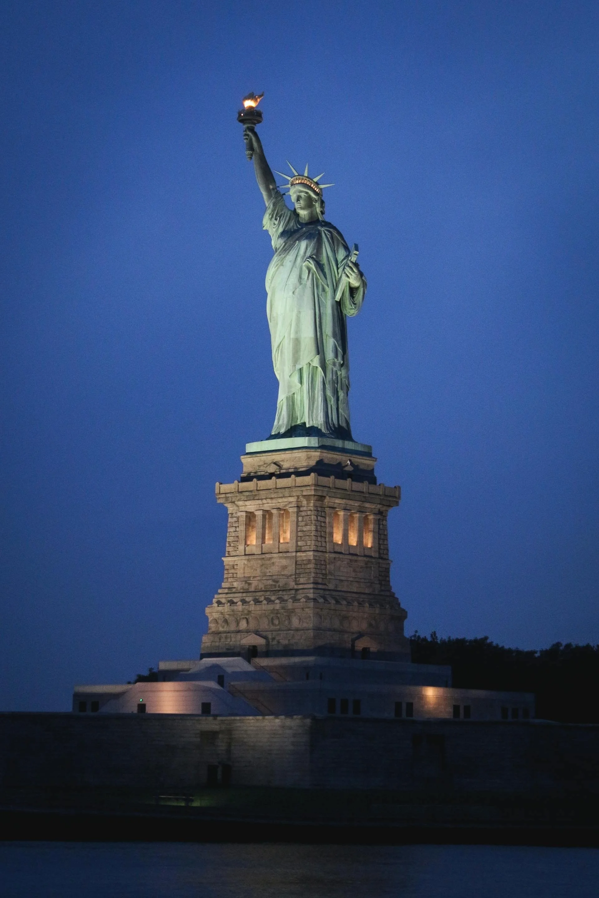 Statue of Liberty at night symbolizing hope, resilience, and new beginnings in the immigration journey.