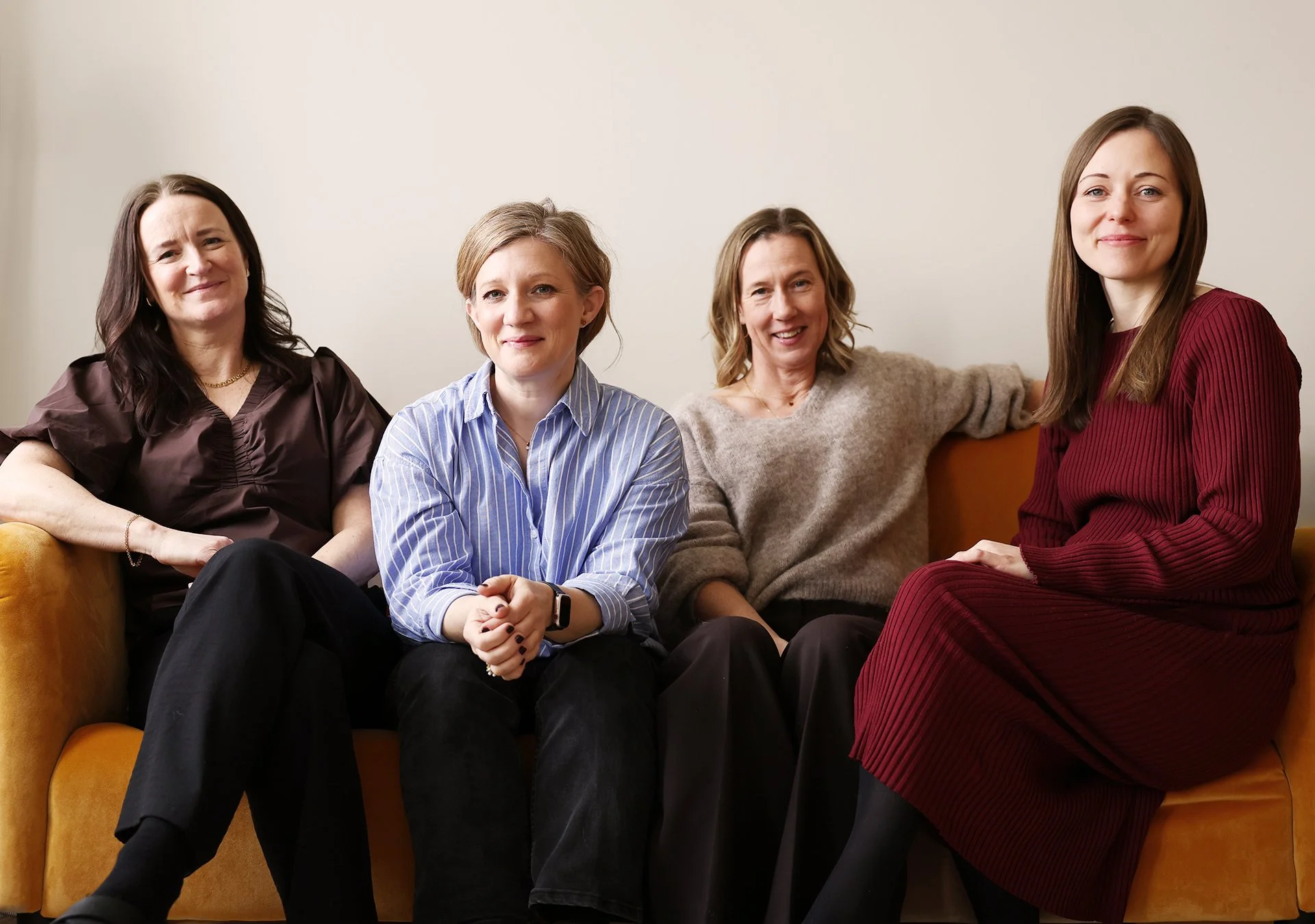 Fyra ur personalen på Stella Barn & Ungdom sittande på en gul soffa och ler mot kameran.