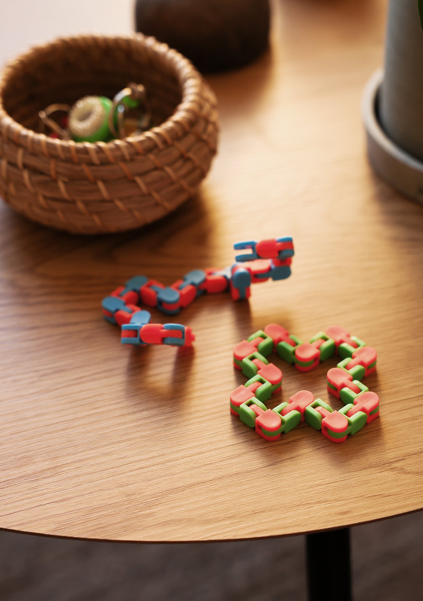 Färgglada leksaker på ett träbord, med en liten korg med nycklar och vaser i bakgrunden.