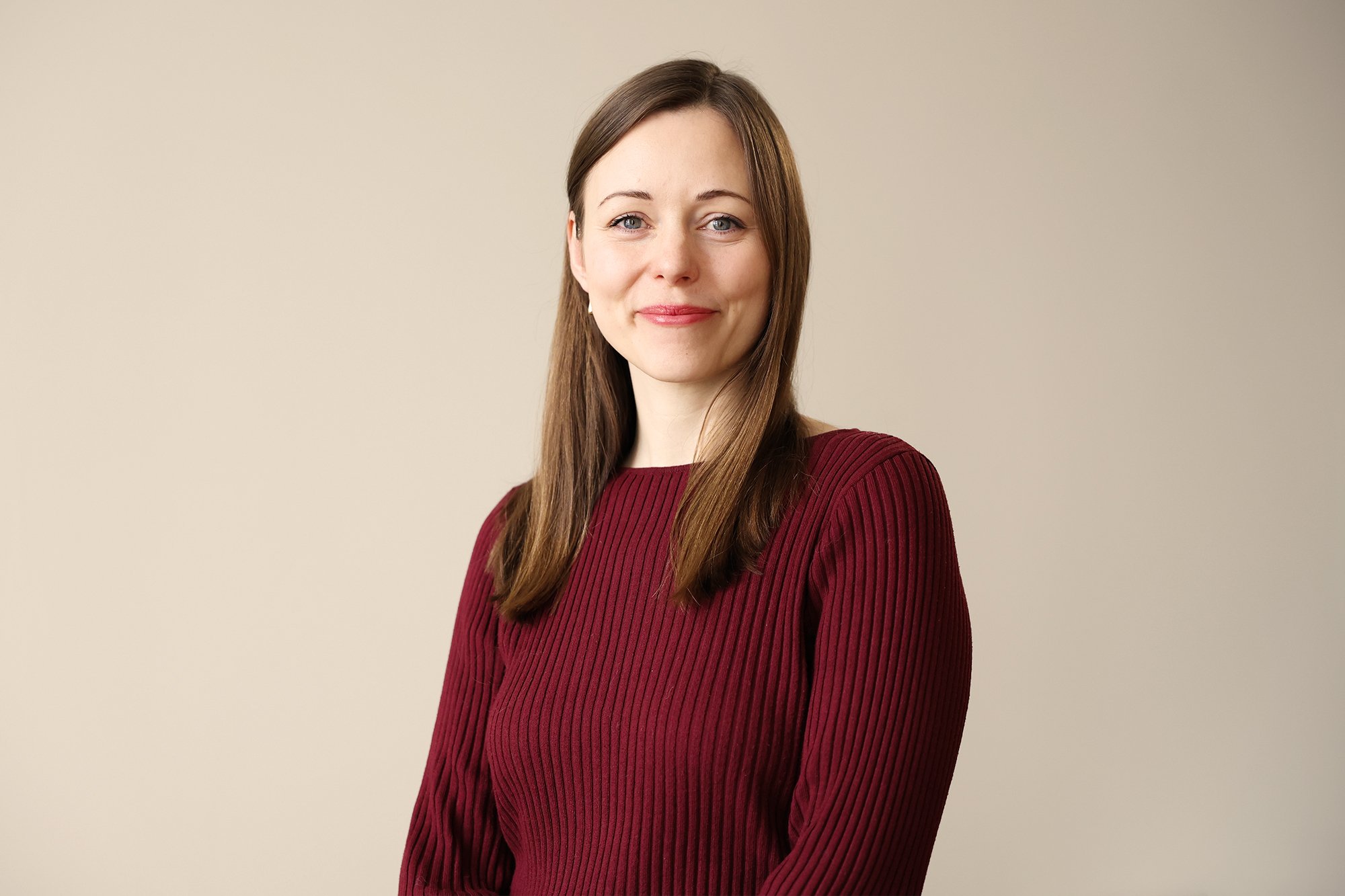 Personal på Stella Barn & Ungdom med brunt, rakt hår, iklädd röd tröja, mot ljus neutral bakgrund.