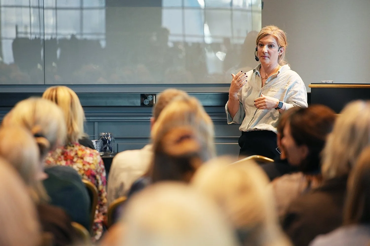 Personal på Stella Barn & Ungdom med headset håller en föreläsning och utbildning för en grupp föräldrar i ett konferensrum.