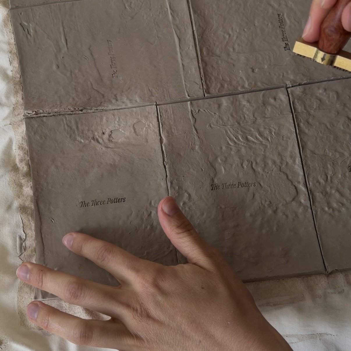 Stamping Logo on clay The Three Potters