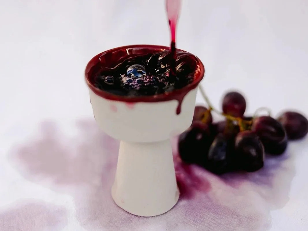 Handmade white stoneware wine cup with red glaze on the inside driping over on the outside