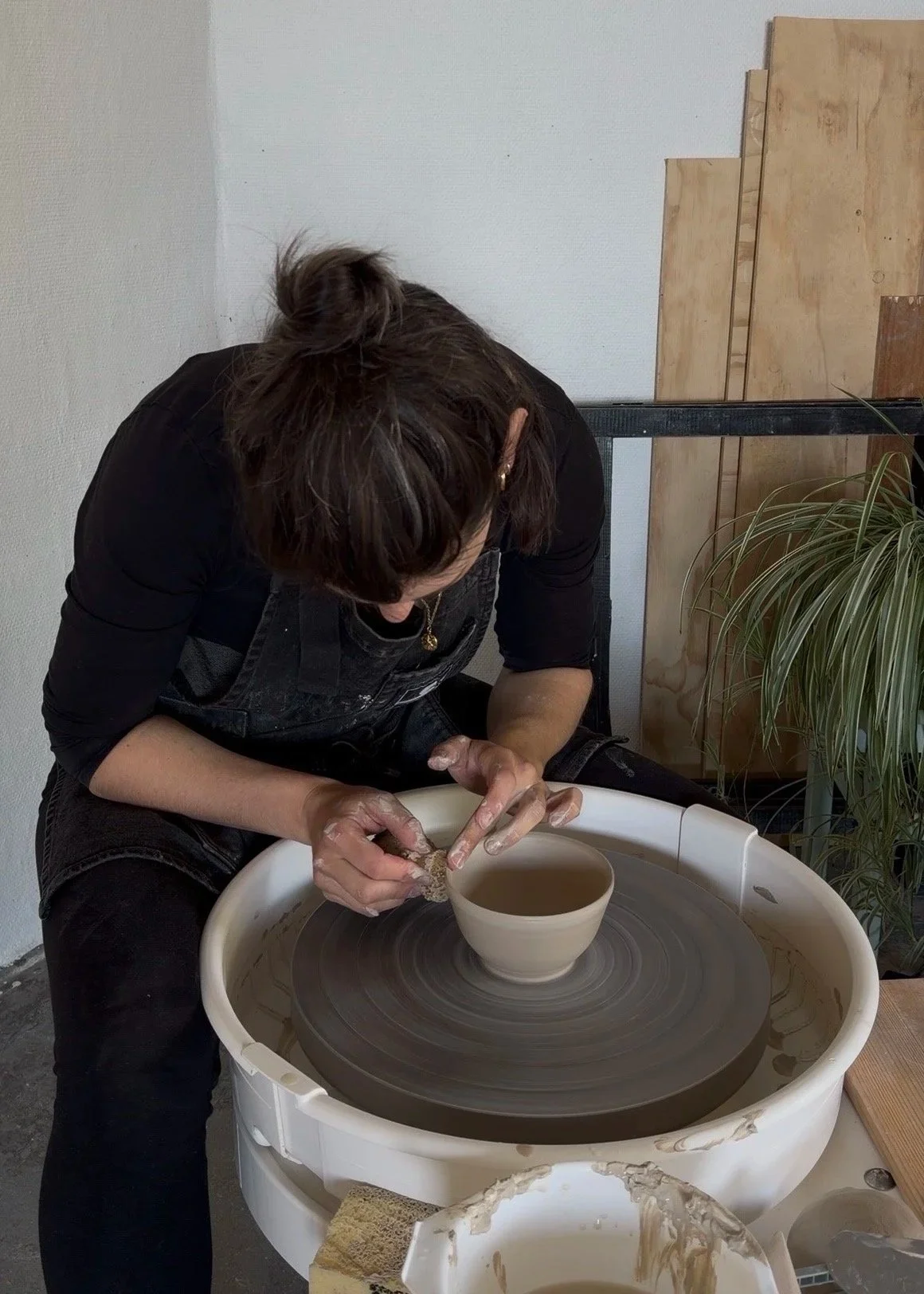 Working on a wheel-thrown stoneware cup in the studio