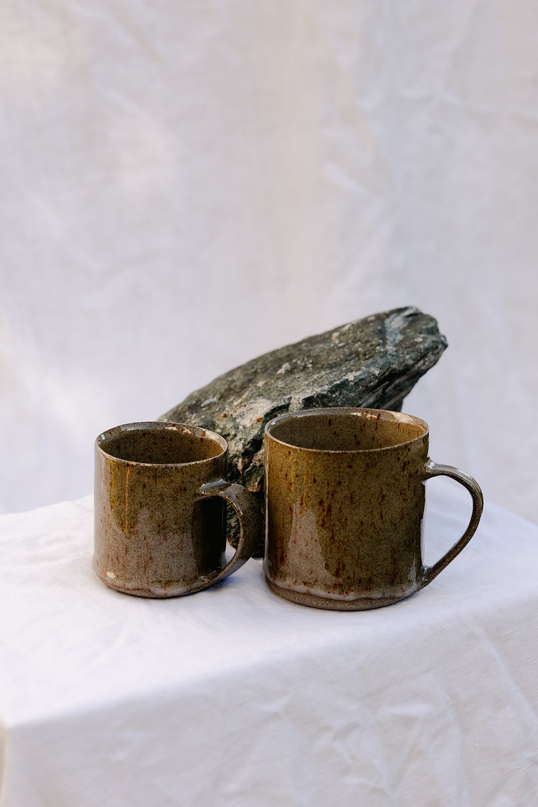 two sized mugs made with grey stoneware and a clear dripping glaze running over it