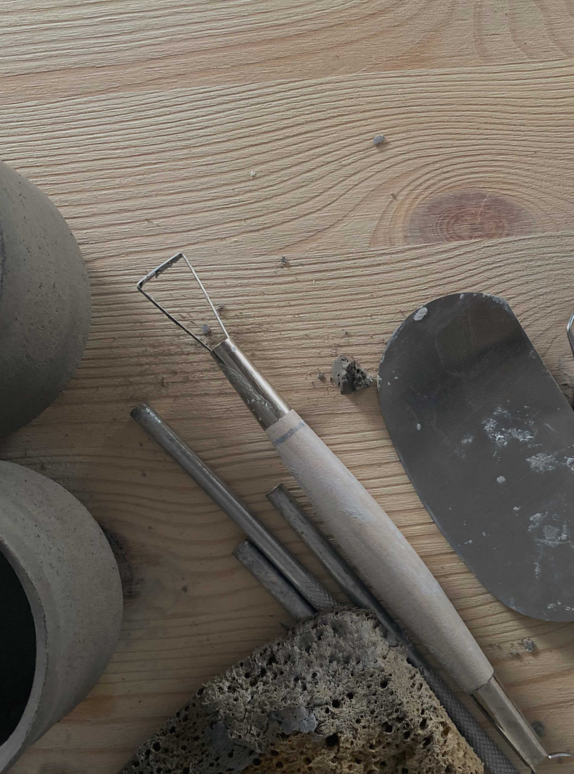 Potter's tools laying next to the cups in process
