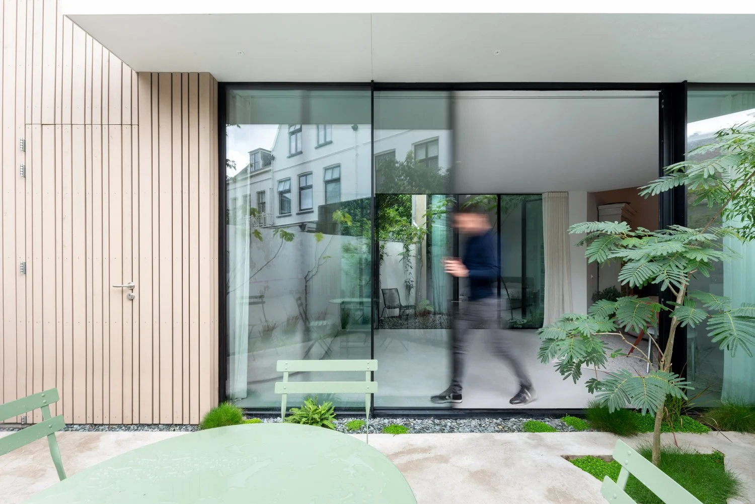 Man schuif glazen schuifdeur open in monumentaal huis