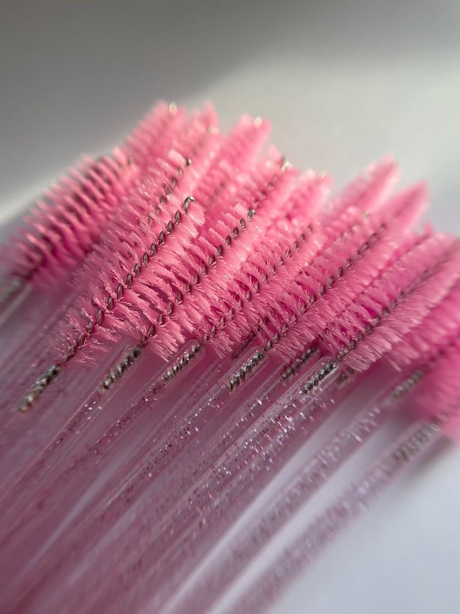 Close-up of pink cleaning brushes with bristles and silver handles arranged in parallel.