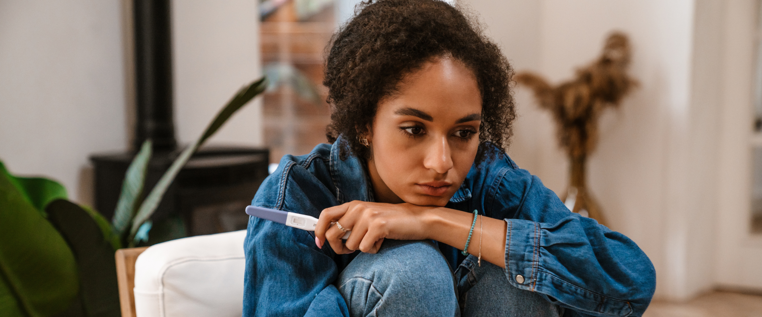 A woman holding a pregnancy test and looking anxious