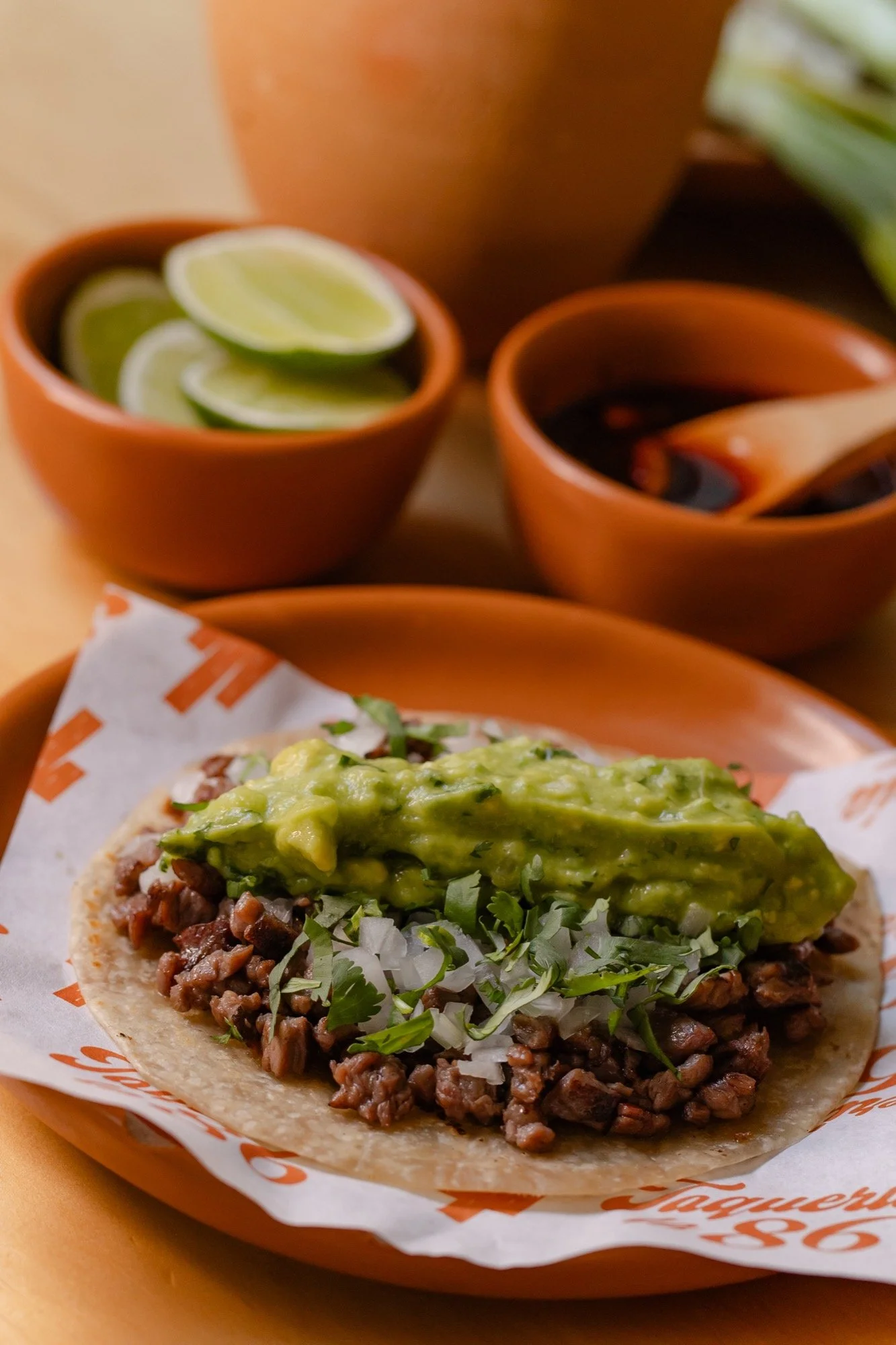 Taco de carne asada norteña con cebolla, cilantro y guacamole en tortilla de maíz
