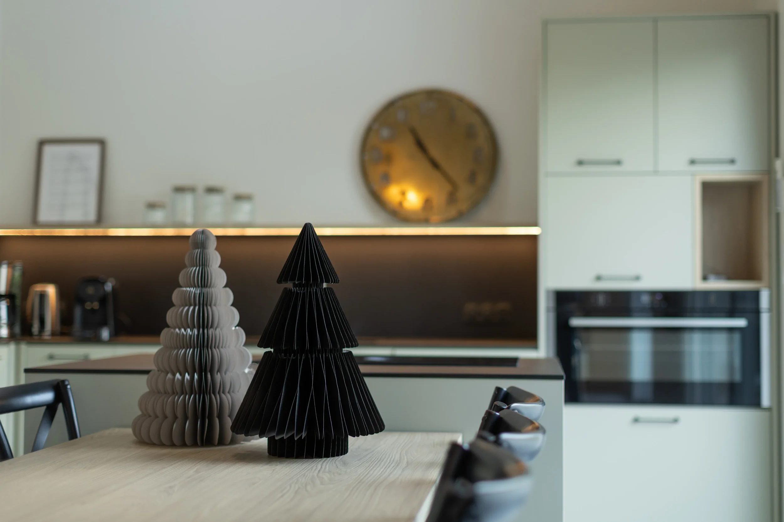 Décoration de Noël avec deux arbres en papier sur une table dans une cuisine moderne.