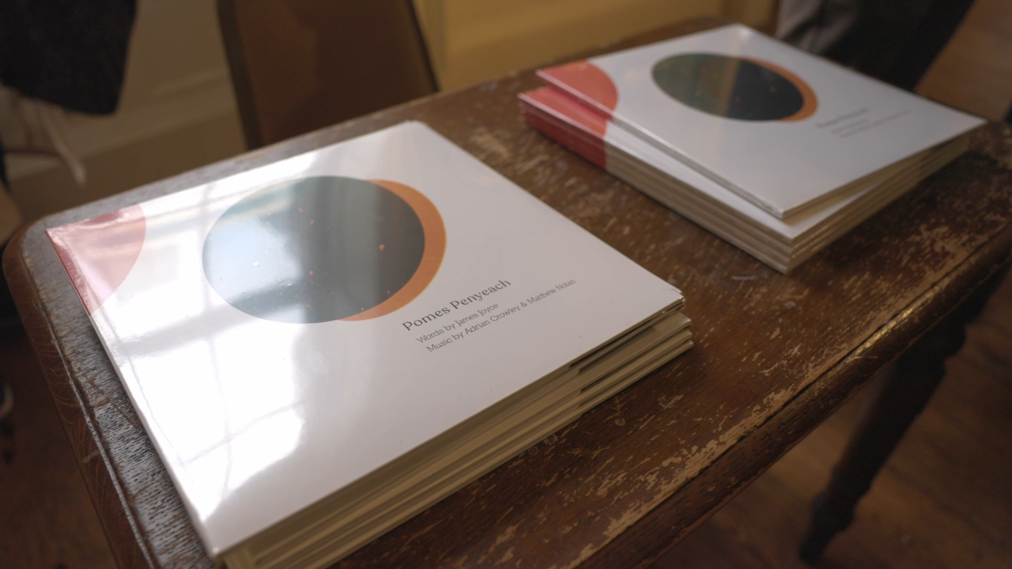Stack of vinyl records titled 'Pomes Penyeach' on a wooden table.
