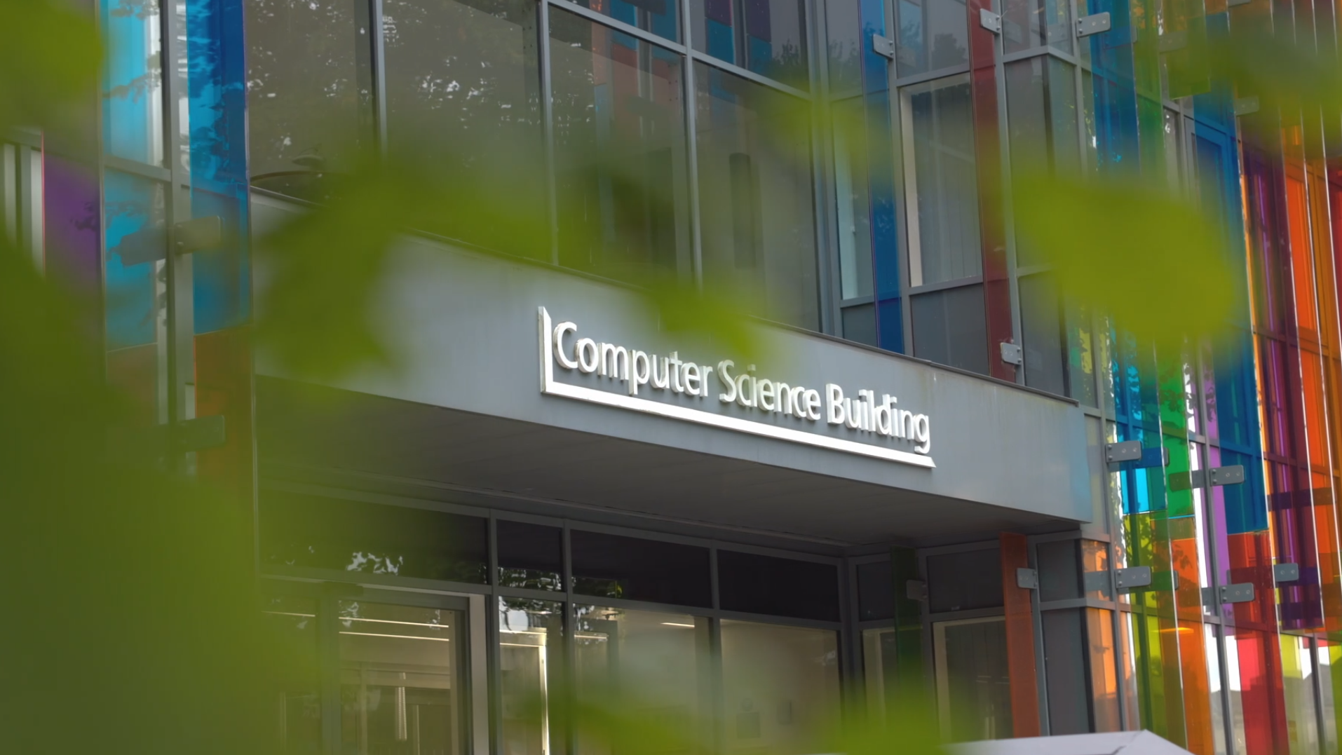 Exterior of a modern building labeled 'Computer Science Building' with colorful glass panels.