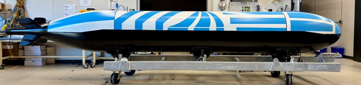 A blue and black streamlined vehicle or prototype on a wheeled platform in a laboratory setting.