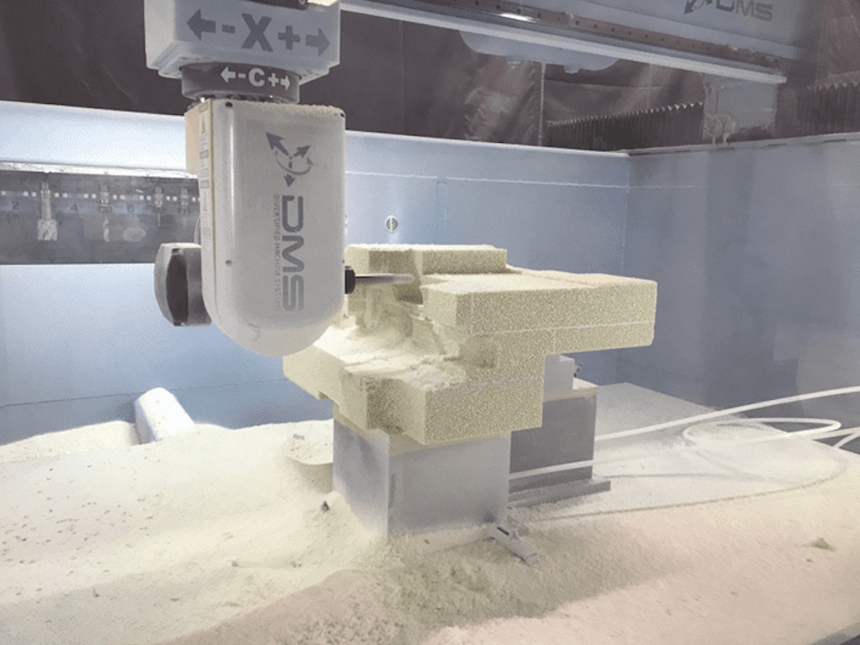 A CNC machine carving a piece of foam material in a manufacturing setting.