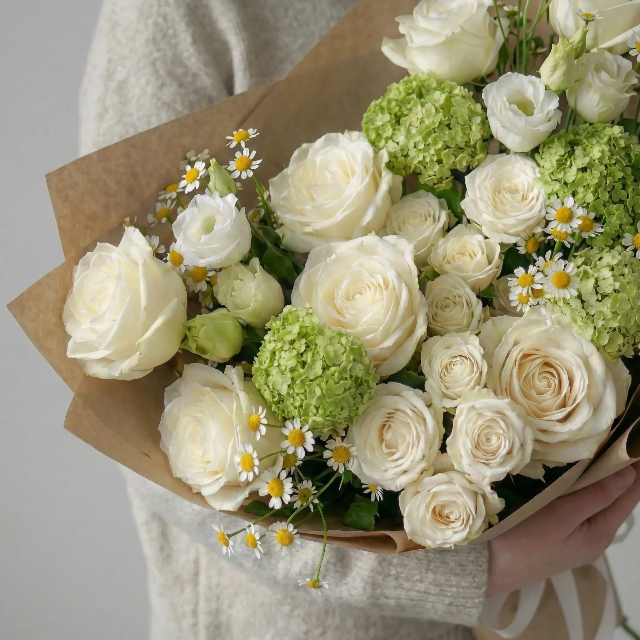 HORA Flowers seasonal white bouquet wrapped in brown paper, styled on a soft grey background