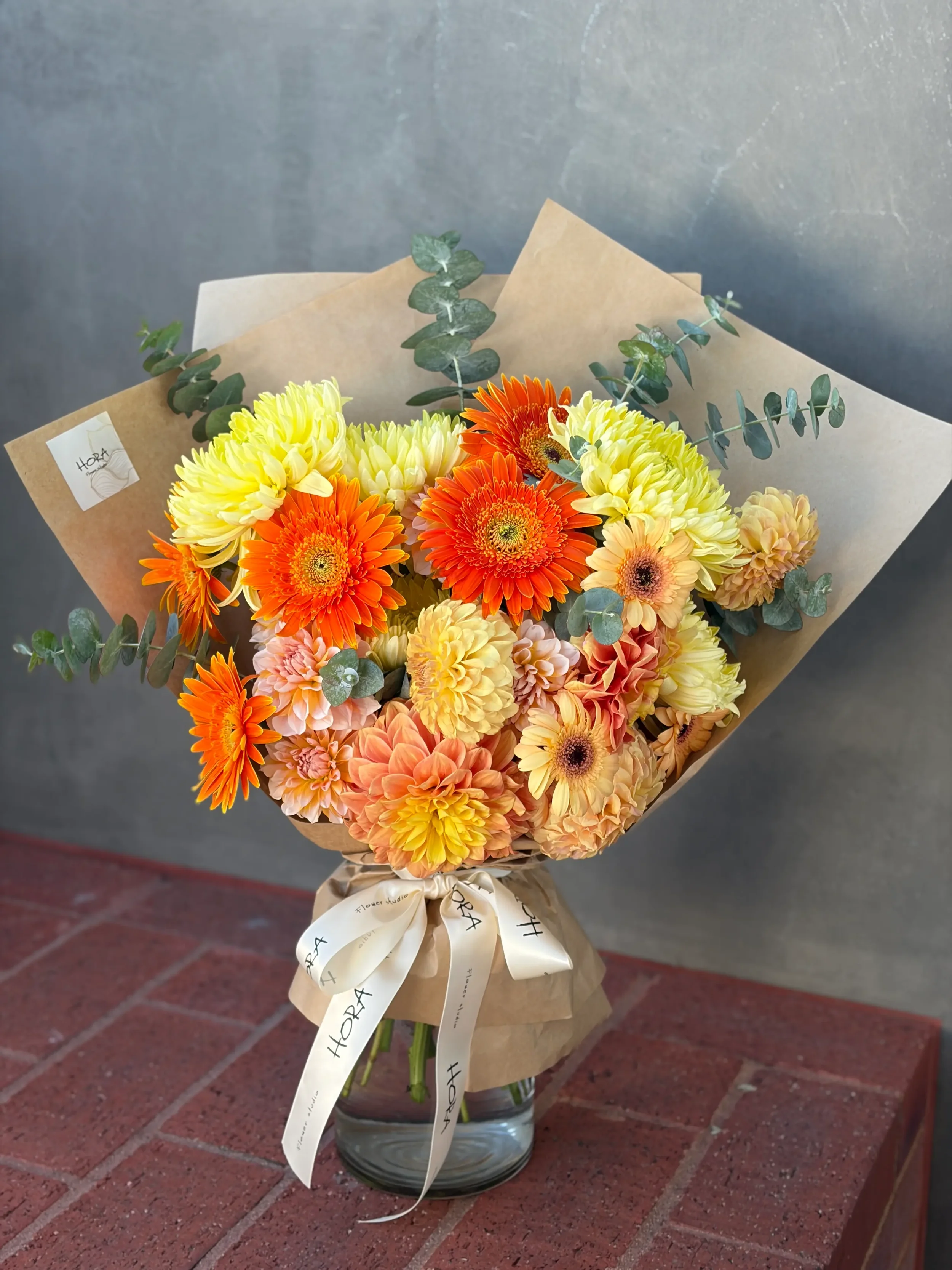 Seasonal bouquet held by model by HORA Flowers Perth in warm orange and yellow tones