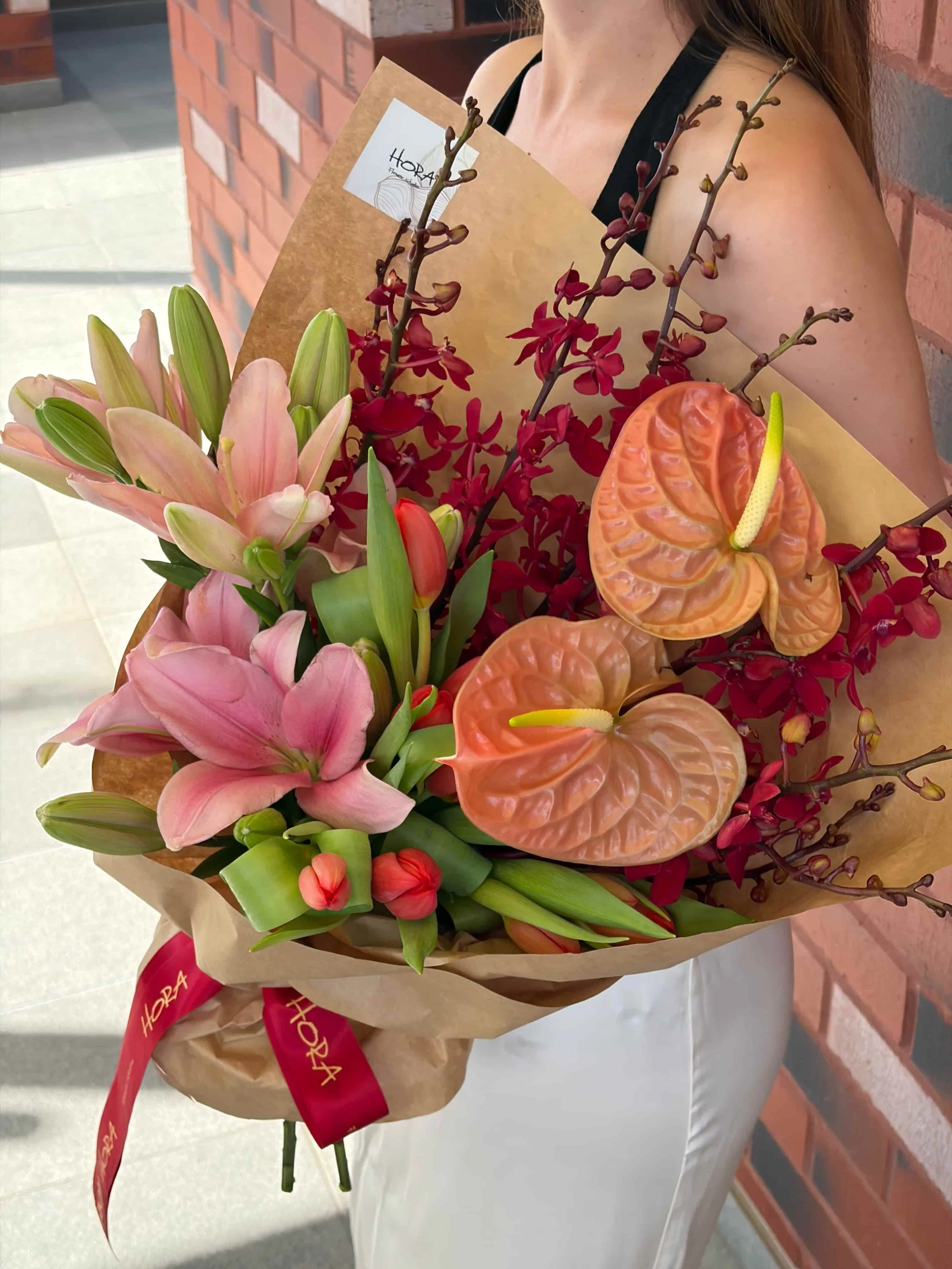Angled view of wrapped pink lily and anthurium bouquet by HORA Flowers Perth