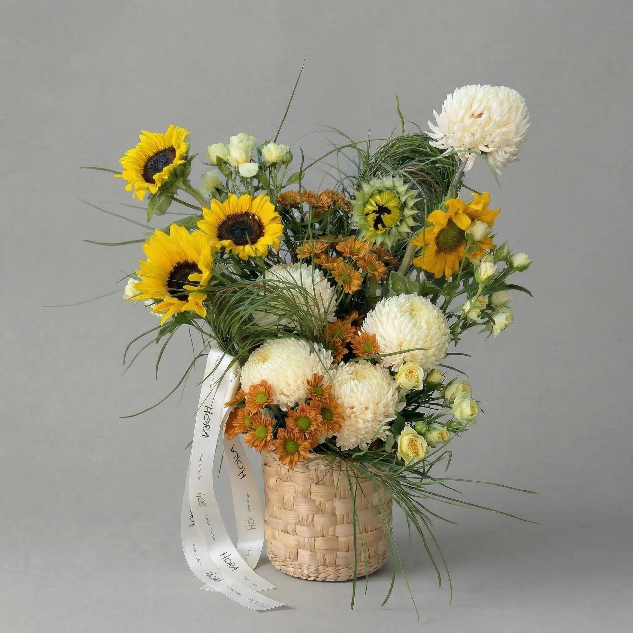 Seasonal sunflower basket arrangement by HORA Flowers in Perth, photographed in a clean grey studio setting.