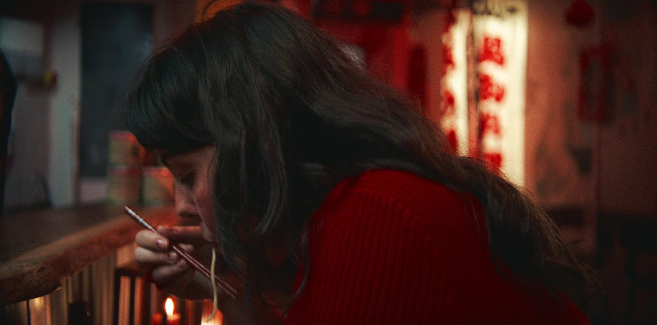 Femme asiatique mangeant des nouilles avec des baguettes dans un restaurant asiatique traditionnel.