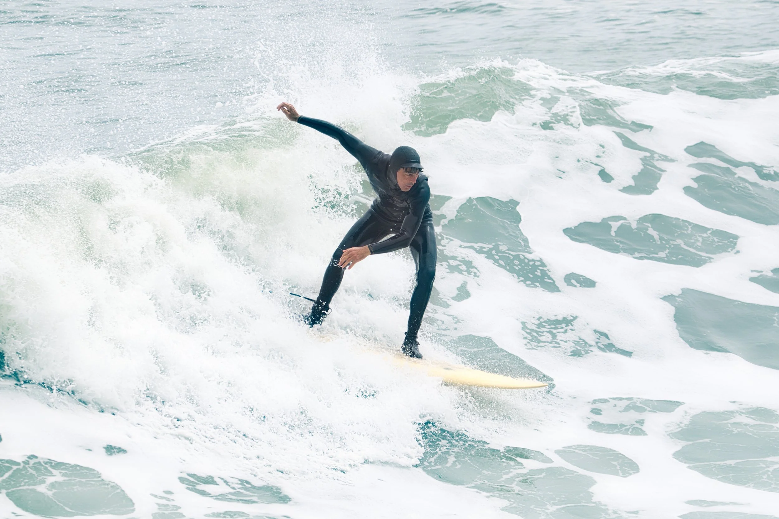 A person in a wetsuit surfing on a wave in the ocean.