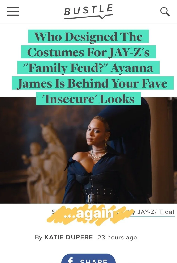 Screenshot of a Bustle article with a headline about who designed costumes for Jay-Z's family feud, featuring a woman with jewelry wearing dark clothing in front of a classical statue.