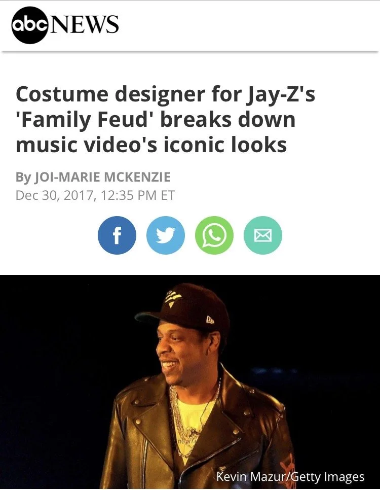 A news article headline from ABC News about a costume designer for Jay-Z's 'Family Feud' music video, featuring a photo of Jay-Z wearing a black leather jacket, a black cap, and jewelry, smiling at night.