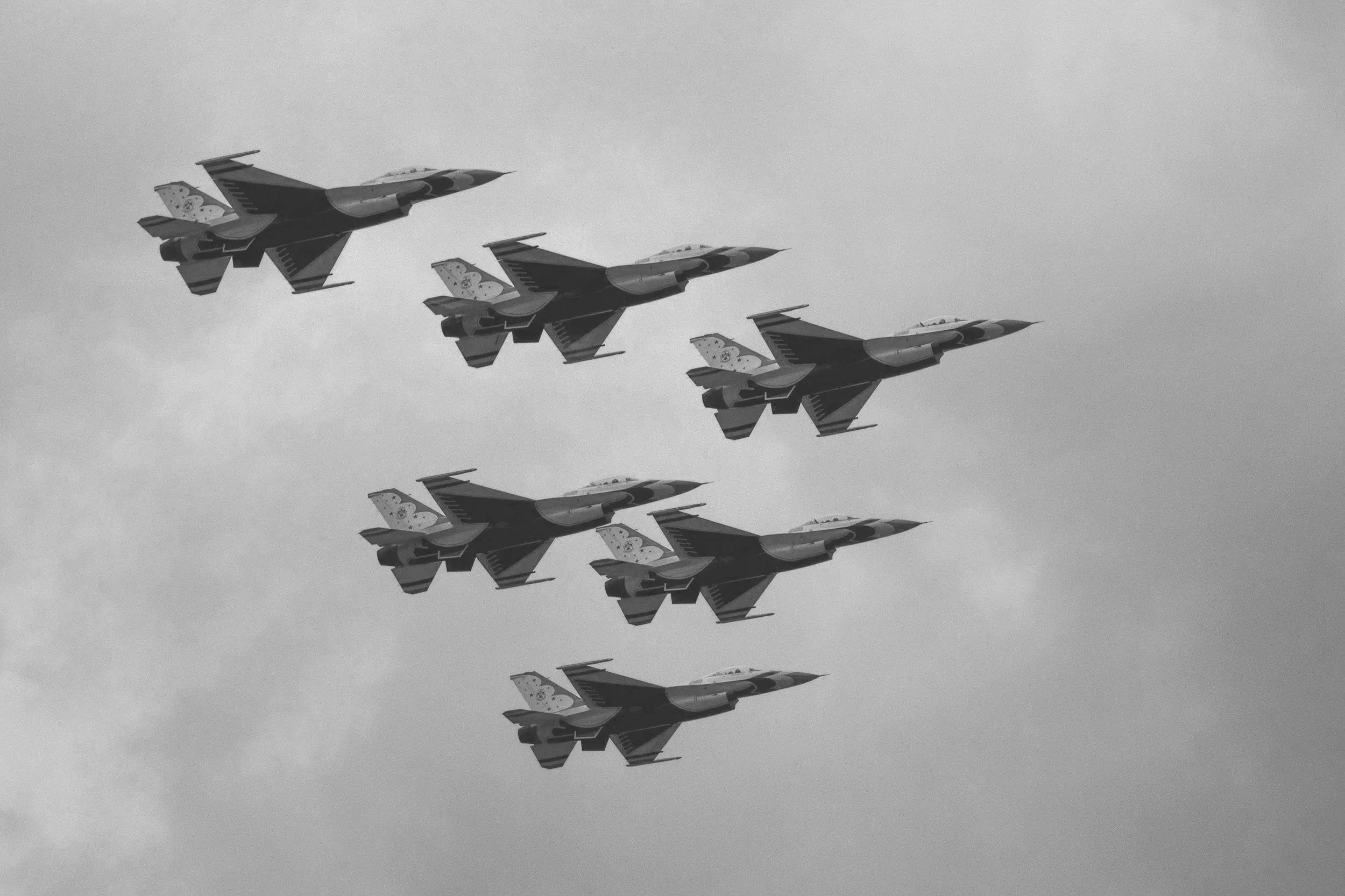 A formation of military fighter jets flying through the sky in a synchronized pattern.