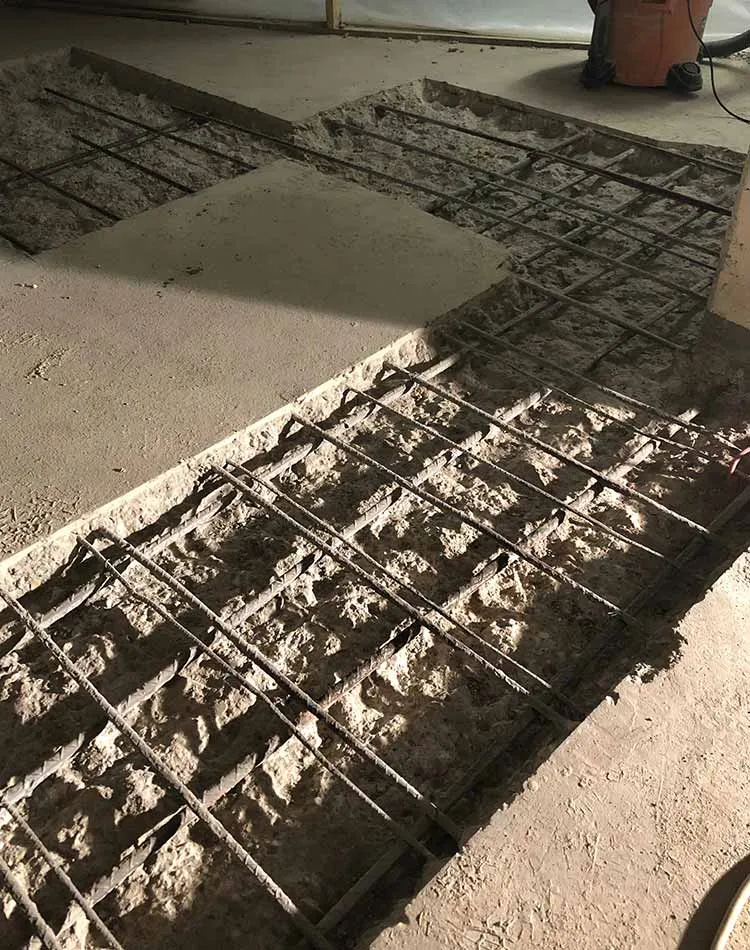 Concrete foundation with exposed steel reinforcement bars, part of an under-construction floor or slab.