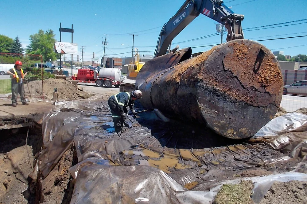 Construction workers repairing a water pipe with heavy machinery and excavation equipment at a construction site.