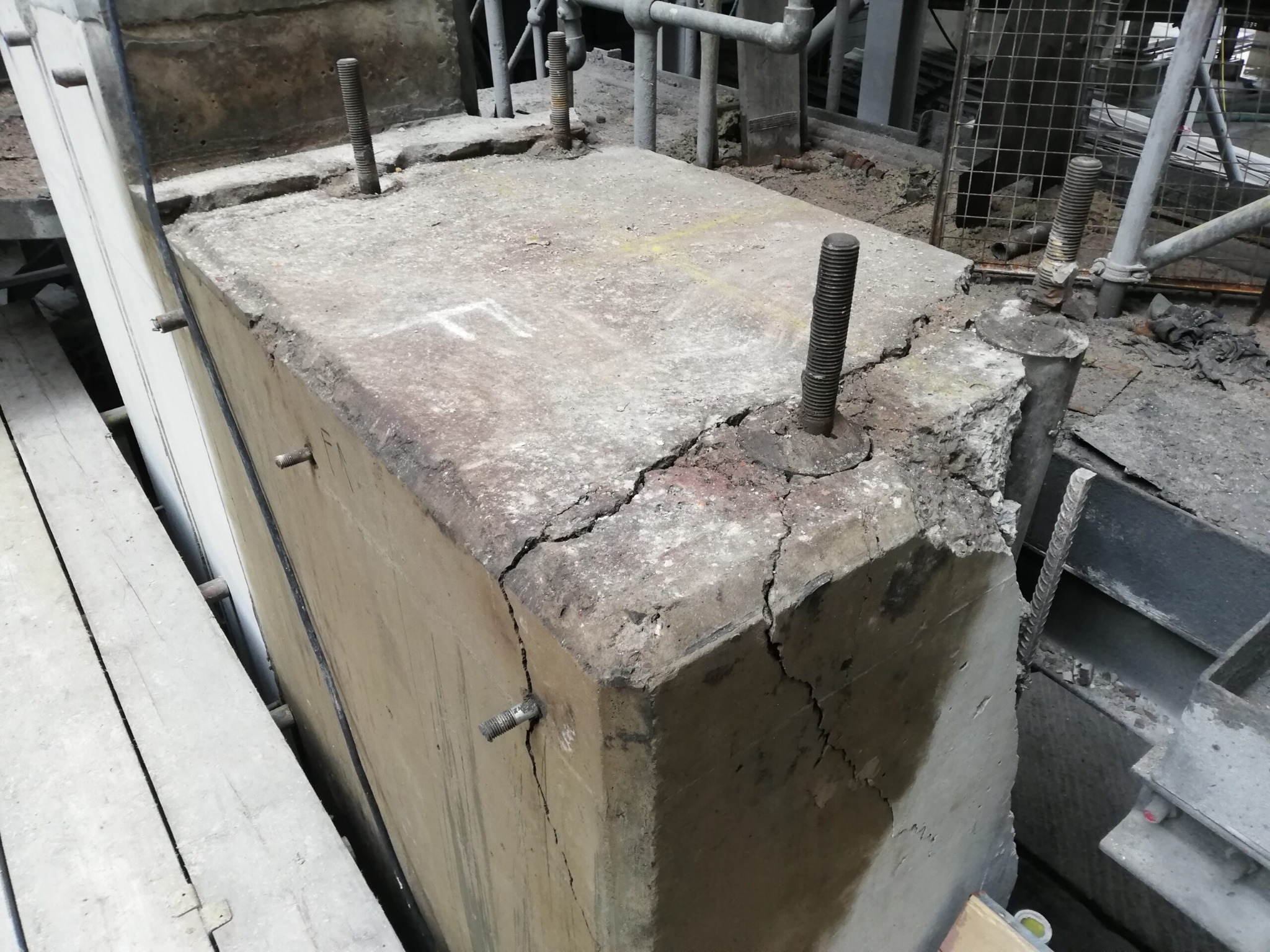 Cracked concrete block with protruding rebar at a construction site.