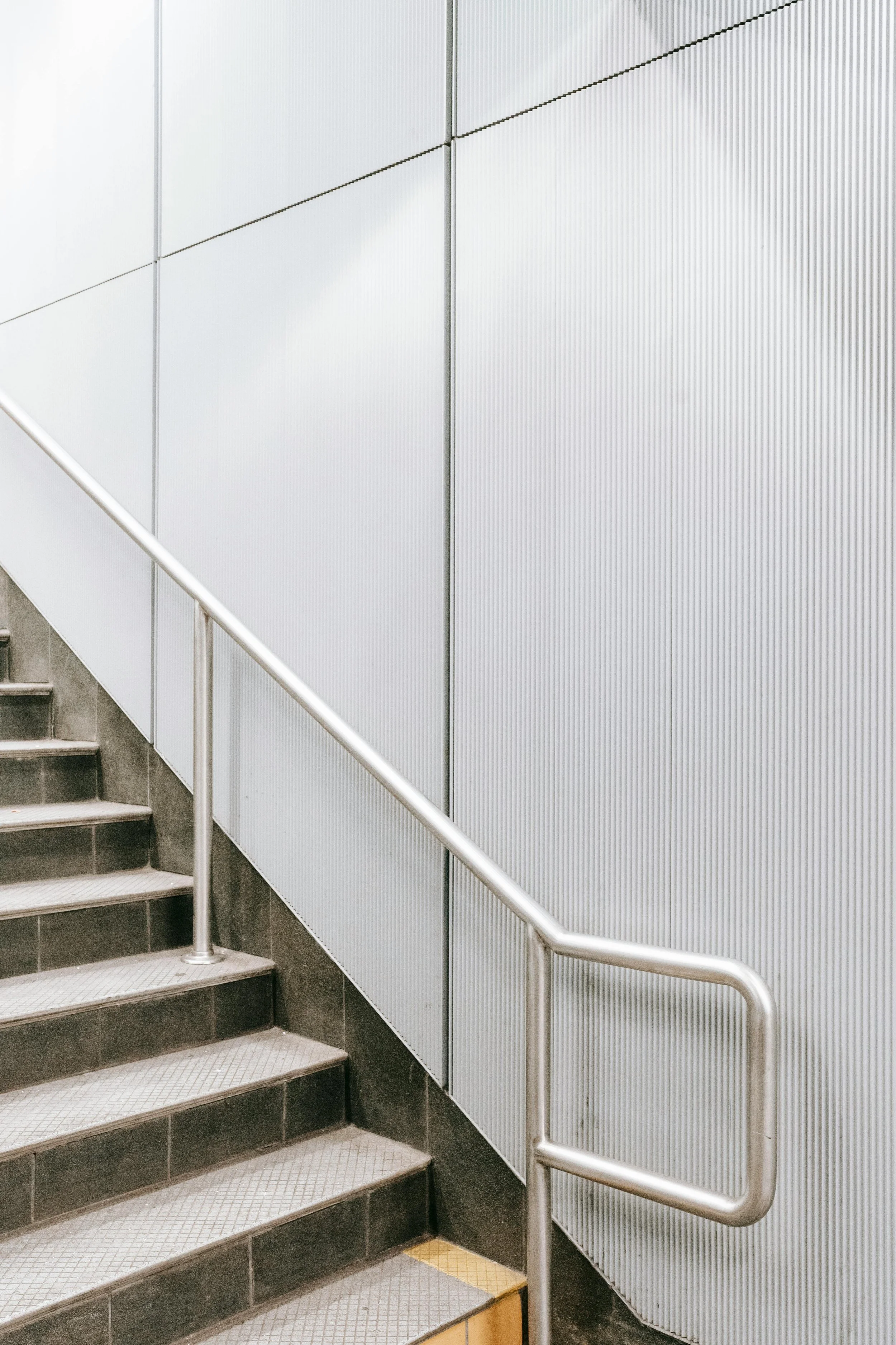 Staircase with metal handrail and textured metal wall panels.