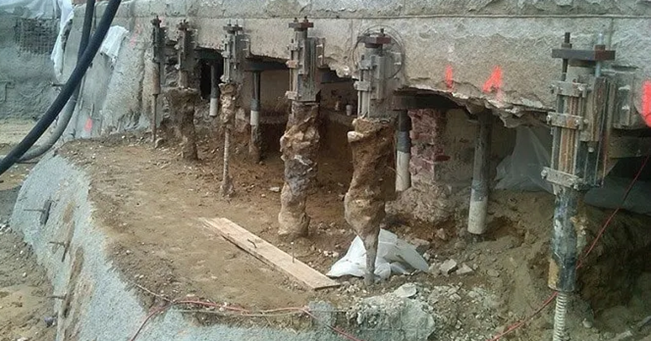 Construction site with exposed concrete wall and structural supports.