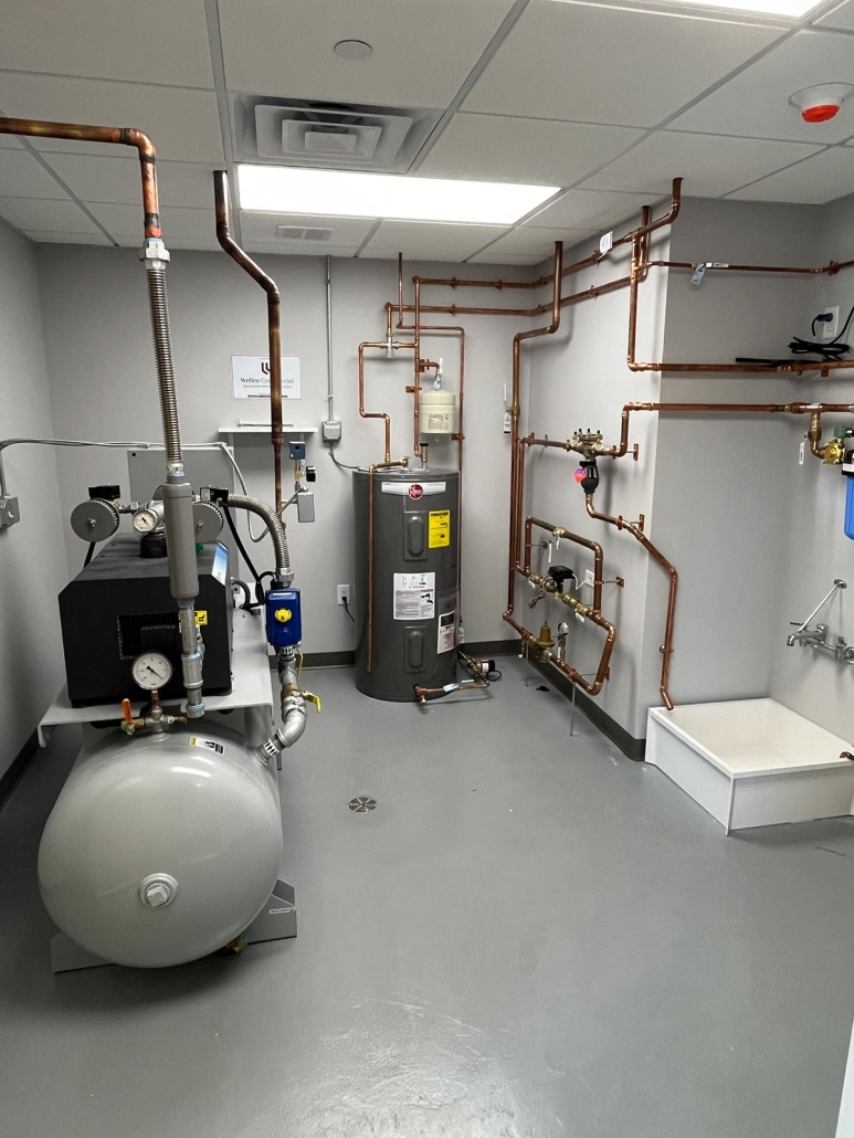 A utility room with copper pipes, a water heater, an air compressor, and a utility sink.